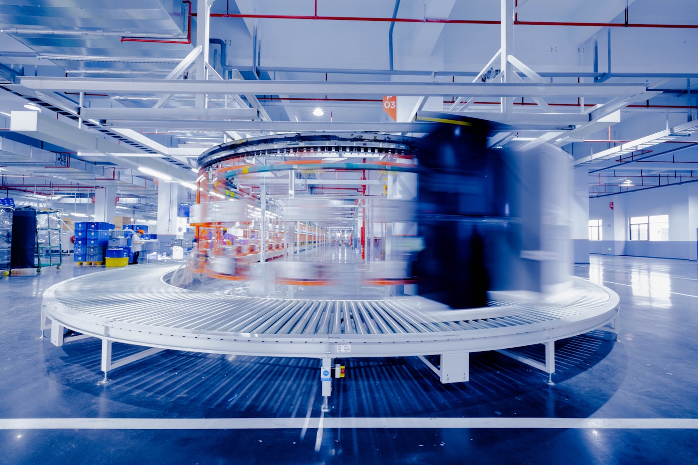 Packages move rapidly on a conveyor belt in a busy warehouse.
